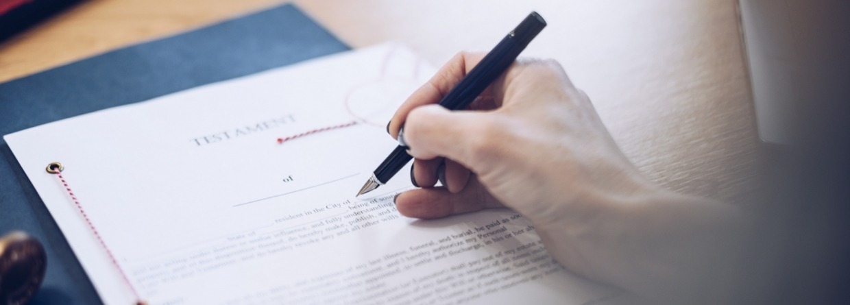 Een vrouw achter een bureau met een testament voor haar en een pen in haar hand